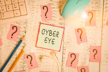 Word writing text Cyber Eye. Business photo showcasing tool engages in building smart technologies in cybersecurity Writing tools, computer stuff and scribbled paper on top of wooden table