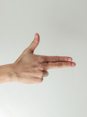 Female hand shows a gun gesture on a white background