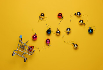 Christmas shopping. Shopping cart, christmas balls on red background. Top view