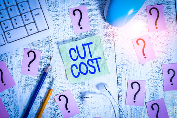 Word writing text Cut Cost. Business photo showcasing Measures implemented to reduced expenses and improved profit Writing tools, computer stuff and scribbled paper on top of wooden table