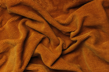 Rumpled orange corduroy fabric texture. Crumpled Background