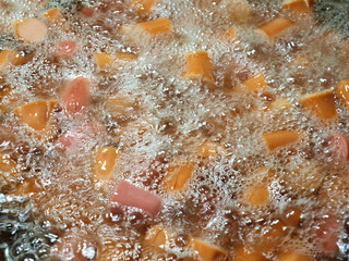Closeup Hot Dogs fried in boiling oil and the oil bubble.