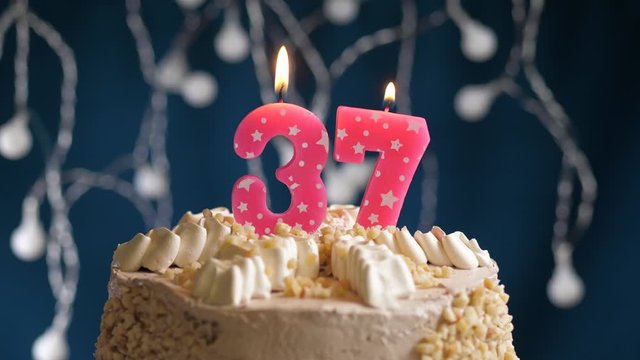 Birthday cake with 37 number pink candle on blue backgraund. Candles blow out. Slow motion and close-up view