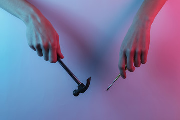 Hand holds hammer and screwdriver. Creative pop art pink blue neon color. Trendy gradient illumination.