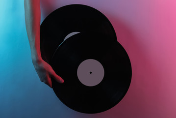 Retro wave 80s. Hand holding vinyl records. Creative pop art pink blue neon color. Trendy gradient...