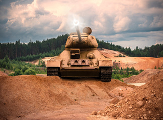 A war scene of the front side of a tank on a gravel hill shooting on a sunset landscape
