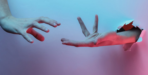 Mystical halloween concept. Hand through a torn hole. Creative pop art pink blue neon color. Trendy gradient illumination. Night light
