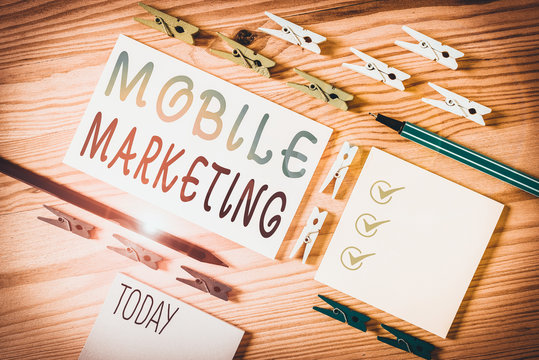 Conceptual hand writing showing Mobile Marketing. Concept meaning promotional activity designed for delivery to cell phones Colored crumpled papers wooden floor background clothespin