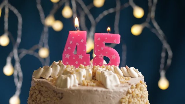 Birthday cake with 45 number pink candle on blue backgraund. Candles blow out. Slow motion and close-up view