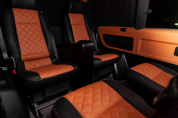 Four rear seats in a minibus are deployed to each other and tightened in black and brown leather...