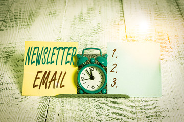 Conceptual hand writing showing Newsletter Email. Concept meaning email sent to subscribers informing them about the news Mini blue clock standing above buffer wire between two paper