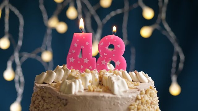 Birthday cake with 48 number pink candle on blue backgraund. Candles blow out. Slow motion and close-up view