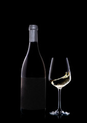 A bottle of precious white wine along with a glass. The wine in the glass moves and creates a dynamic effect.