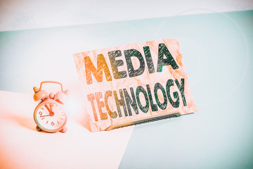 Text sign showing Media Technology. Business photo text process of huanalysis origin that used to convey media Mini size alarm clock beside a Paper sheet placed tilted on pastel backdrop