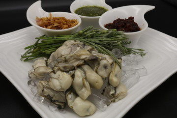 Fresh oyster with seafood sauce, chili paste and acacia on white plate