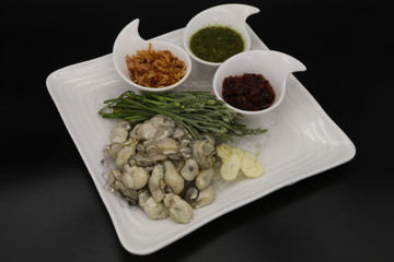 Fresh oyster with seafood sauce, chili paste and acacia on white plate