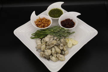 Fresh oyster with seafood sauce, chili paste and acacia on white plate