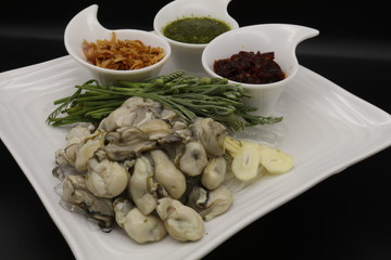 Fresh oyster with seafood sauce, chili paste and acacia on white plate