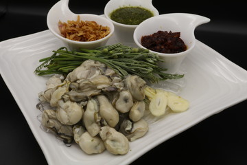 Fresh oyster with seafood sauce, chili paste and acacia on white plate
