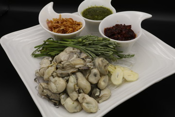 Fresh oyster with seafood sauce, chili paste and acacia on white plate