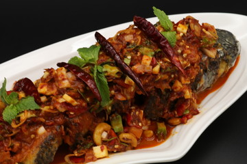 Thai spicy fried fish with herbs and chili on white plate