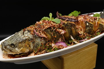Fried fish with spicy salad and herbs on white plate