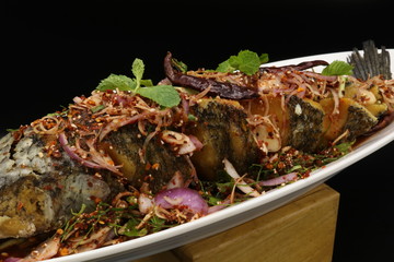 Fried fish with spicy salad and herbs on white plate