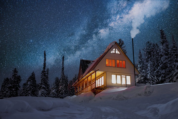 Wooden house with light in window. Fantastic night landscape in winter