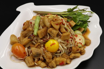 Somtum (Thai spicy salad) with pork rind and vegetable in white plate