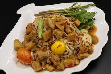Somtum (Thai spicy salad) with pork rind and vegetable in white plate