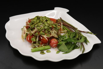 Somtum (Thai spicy salad) with acacia seeds and vegetable in white plate