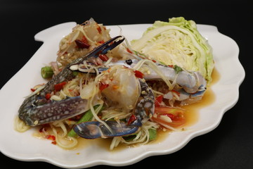 Somtum (Thai spicy salad) with raw crab and vegetable in white plate