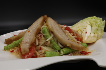 Somtum (Thai spicy salad) with grilled pork neck and vegetable in white plate