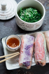Closeup of vietnamese spring rolls with vegetable filling, dip sauce and seaweed salad, vertical shot