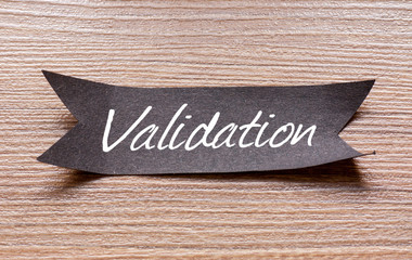 Validation word written on Black papper with wooden background