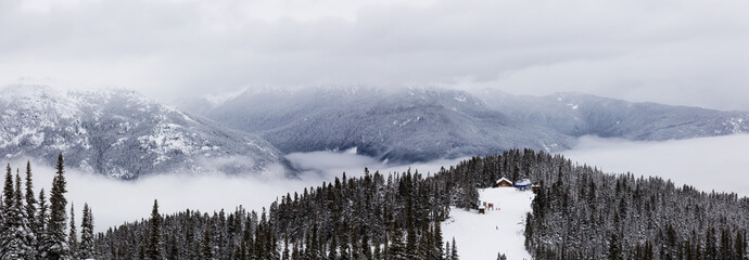 Obraz premium Whistler, British Columbia, Canada. Beautiful Panoramic View of the Canadian Snow Covered Mountain Landscape during a cloudy and foggy winter day.