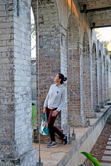 Fototapeta na wymiar A young woman standing among the stone columns in Paddington Reservoir Gardens is an urban oasis in the city center in Sydney. It is a heritage-listed public park.