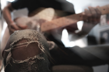 Obraz premium tear of jeans and blur of young musician playing Electric Guitar, play the music instruments. with soft focus and selective focus