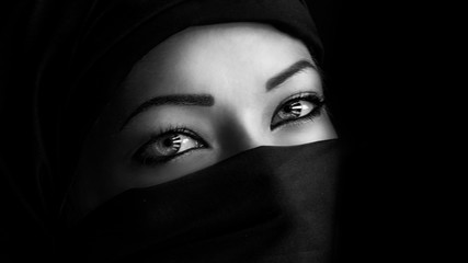 Young woman in hijab on black background