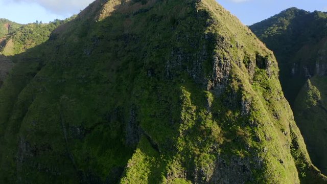 4K aerial drone shot of a high green mountain in the sunset light, tropical Hawaiian island Kauai
