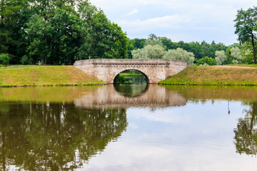Fototapeta na wymiar Stone arch bridge across a lake in Gatchina, Russia