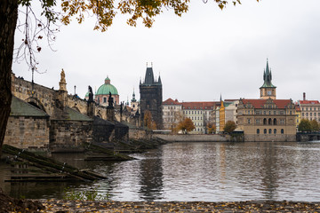 Obraz premium Charles bridge and tower in Prague on a cloudy day in autumn