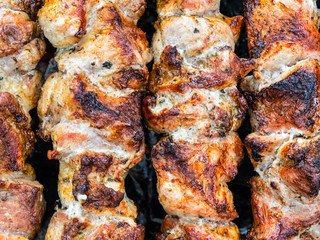 Frying pork on a skewer over a brazier. Turning meat over coals. Appetizing shish kebab.