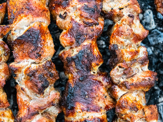 Frying pork on a skewer over a brazier. Turning meat over coals. Appetizing shish kebab.