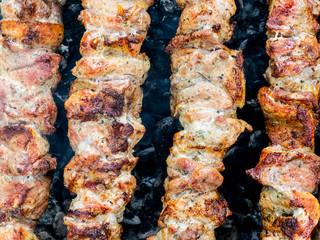 Frying pork on a skewer over a brazier. Turning meat over coals. Appetizing shish kebab.