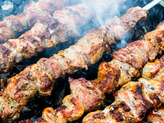 Frying pork on a skewer over a brazier. Turning meat over coals. Appetizing shish kebab.
