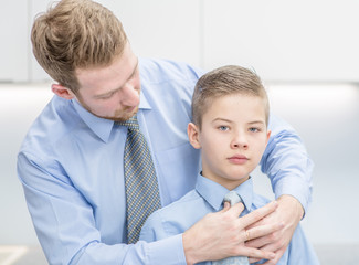 Father helps his son to tying necktie at home