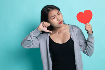 Asian woman thumbs down with red heart.