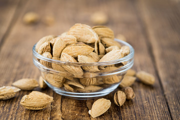 Old wooden table with roasted Almonds (in the shell)
