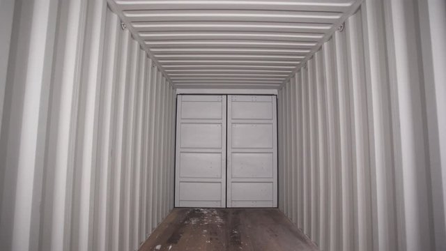 Inside large shipping container. Stock footage. View from inside locked cargo container with white striped iron walls. Empty light and locked cargo trailer container